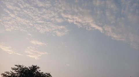 Scenic view of white clouds scattered across a bright blue sky at sunset. Stock Photos