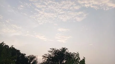 Scenic view of white clouds scattered across a bright blue sky at sunset. Stock Photos