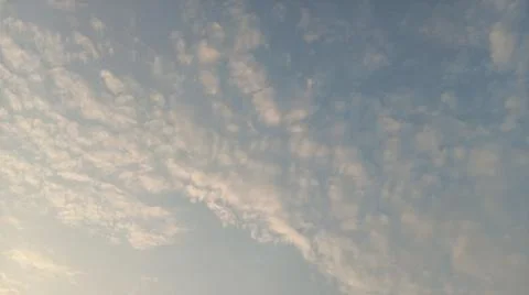Scenic view of white clouds scattered across a bright blue sky at sunset. Stock Photos