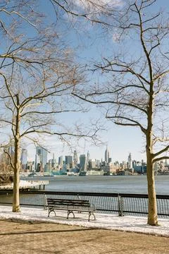 Scenic view of a winter afternoon by the river with city skyline and bare trees Stock Photos