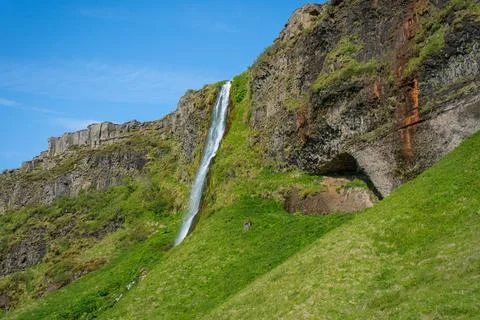 Scenic waterfall cascading down a lush green cliff in Iceland Fotos de archivo