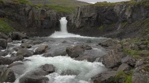 Scenic waterfall cascading over rugged volcanic rocks in the wilderness of Stock Footage 339775726
