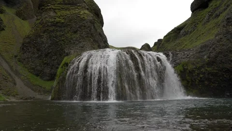 Scenic Waterfall Flowing Over Mossy Cliffs in the Icelandic Wilderness - Stock Footage 339957482