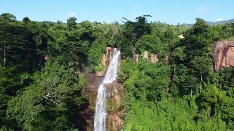 Scenic waterfall surrounded by lush greenery and trees, creating a picturesque Stock Footage 316925344