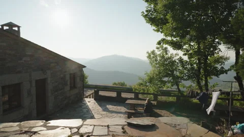 Scenic, wide-angle shot of a rustic stone house with a terrace overlooking a 動画素材 344210056