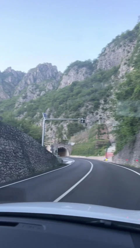 Scenic winding mountain road between steep limestone cliffs and lush green 库存影片 340898546
