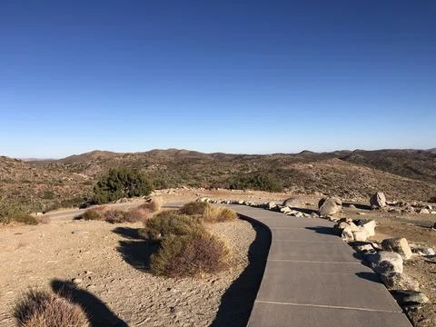 Scenic Winding Path Through Arid Landscape Under Clear Blue Sky Stock Photos