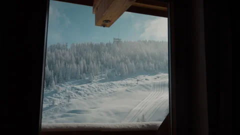 Scenic winter view from a cozy cabin window, overlooking snow-covered alpine Stock Footage 332985947
