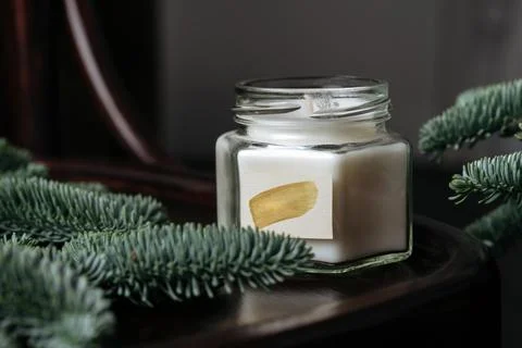 Scented candle, on a table surrounded by spruce branches. New Year mood Фото