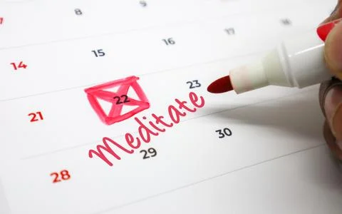 Scheduling a mindful moment Hand marking Meditate on a calendar to prioriti.. Stock Photos