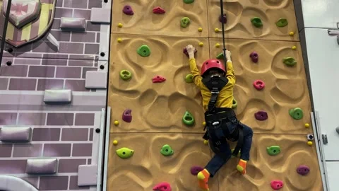 A school age boy climbs the rock climbing wall in the game center. Stock Footage 346721926