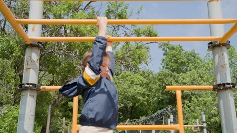 School Age Boy Crossing Yellow Monkey Bars at Park Playground Video stock 328635662