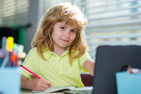 A school age boy does homework at home. Portrait of little schoolboy sitting at Foto stock