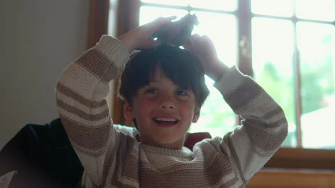 School age boy places toy figurine on head while smiling at restaurant tabl.. Video stock 340976649