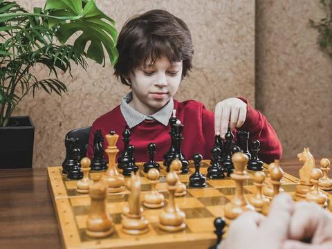 School age Boy playing chess indoors alone Stock Photos