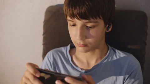 School age boy playing mobile games on mobile phone 库存影片 248040343