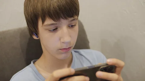 A school-age boy plays games on a mobile phone Video stock 247040871