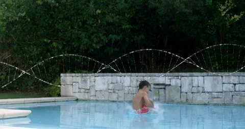 School-age boy stepping onto diving board and generating animated splash Stock Footage 317800992