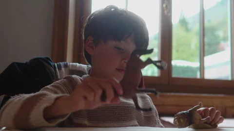 School age boy taps toy on restaurant table while waiting for meal, express.. Stock Footage 340976707