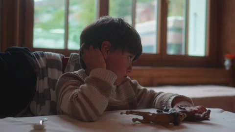 School age boy waits at restaurant table while absentmindedly scratching hi.. Stock Footage 340972152