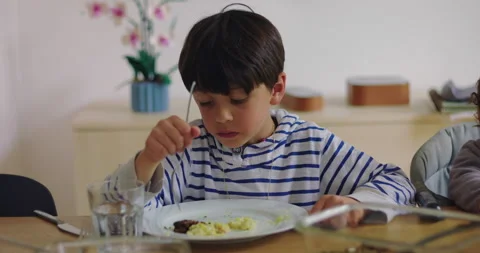 School-age child eats lunch at dining room table, practicing independent me.. Stock Footage 340976050