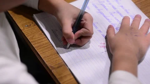 A school-age child writes in a notebook. The child writes with his left hand. Stock Footage 140817661