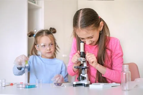 School-age children examine objects under a microscope. Stock Photos