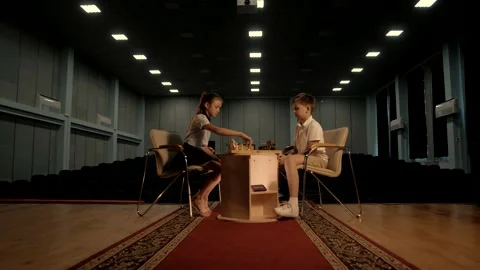 School-age children sit at the table and play chess. Cinematic Stock Footage 156700108