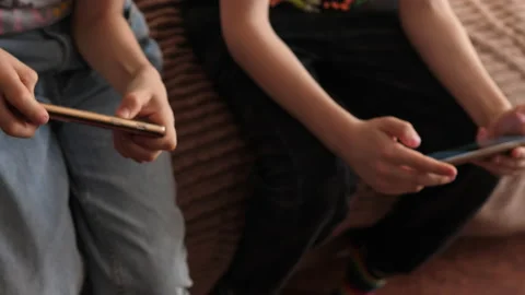 School-age children sitting on the couch use gadgets play mobile games on s.. Stock Footage 237998502