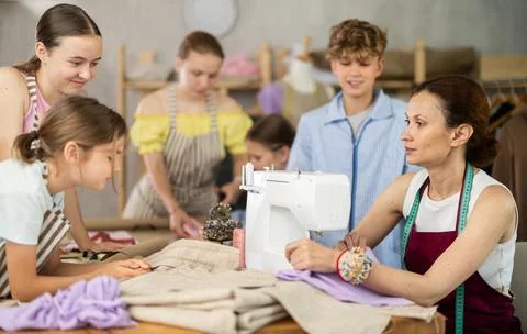 School-age students learning sewing from female instructor in tailoring workshop Stock Photos