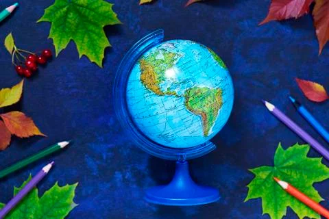 School background from globe and colored autumn leaves and colored pencils Stock Photos