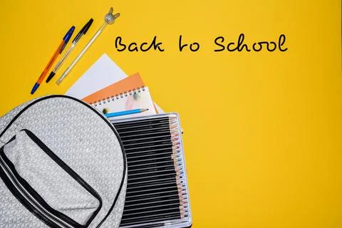 School Backpack with Colored Pencils Notebooks and Pens on Yellow Background Stock-Fotos