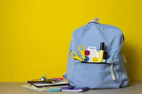 School backpack with stationery on color background Stock Photos