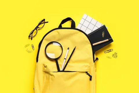 School backpack with stationery on yellow background, top view Stock Photos