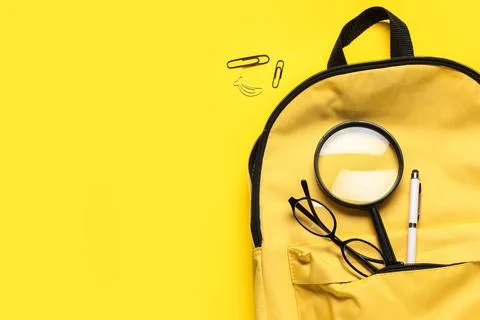 School backpack with stationery on yellow background, top view Stock Photos