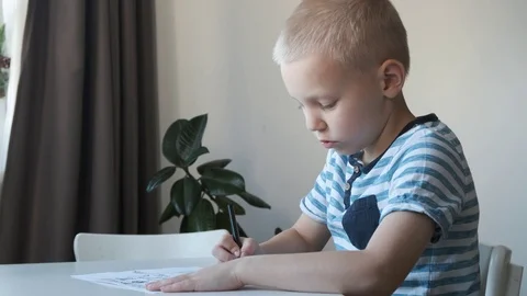 School boy, child, sitting at the table at home and drawing or doing homework Stock Footage 120434185