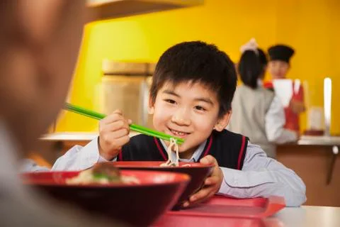 School boy eats noodles in school cafeteria Stock Photos