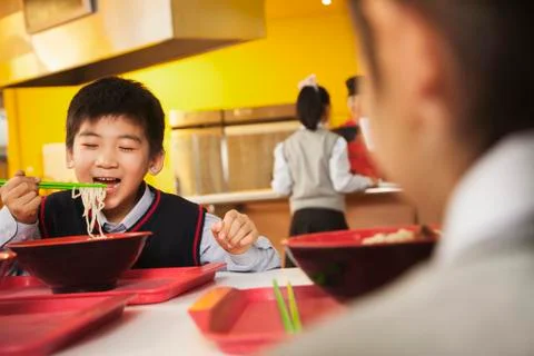 School boy eats noodles in school cafeteria Stock Photos