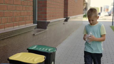 School boy is holding the plastic bottle and puts it to the correct bin fot Stock Footage 204116026