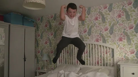 School boy jumping on parents bed in slow motion Stock Footage 114236345