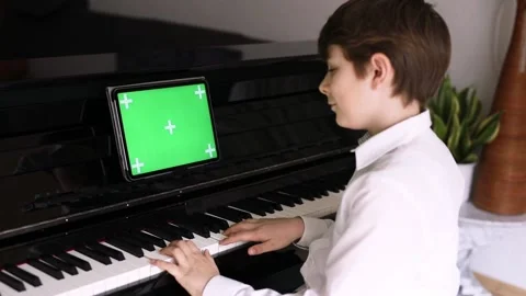 School boy learning play piano with tablet app. Child having fun with learning Stock Footage 154230209