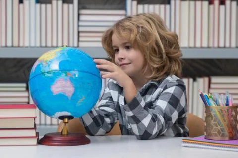 School boy looking at globe in library, geography lesson. School child student Stock Photos