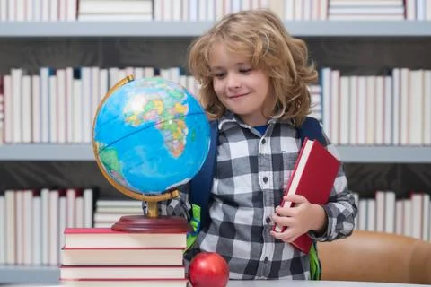 School boy looking at globe in library, geography lesson. School child student Stock Photos