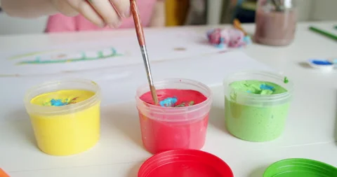 School boy reaching for red paint with paintbrush in his hand. Stock Footage 130752738