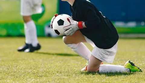 School boy as a soccer goalie catching football ball during a tournament game Stock Photos