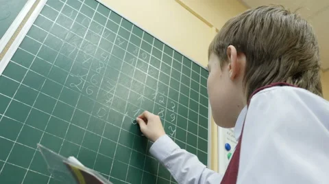 School boy solves math on the blackboard at primary school, 4k shot Video stock 62500675