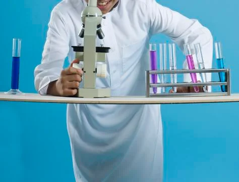 School boy using a microscope with chemicals in test tubes Stock Photos