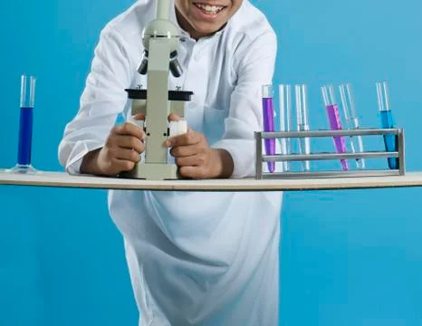 School boy using a microscope with chemicals in test tubes Stock Photos