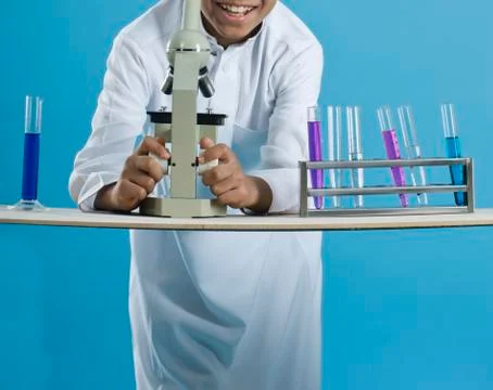 School boy using a microscope with chemicals in test tubes Foto stock