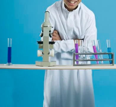 School boy using a microscope with chemicals in test tubes Stock Photos
